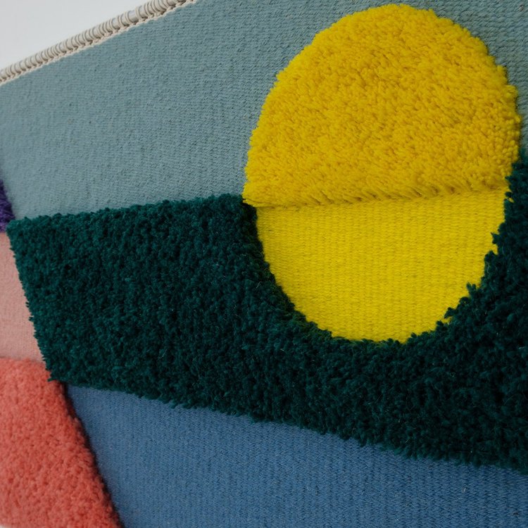 Opera tessile contemporanea tessuta a mano da Ilary Bottini, paesaggio astratto con toni di azzurro, blu, verde, rosa, viola e giallo con campiture geometriche orizzontali, diagonali e circolari a alternanza di sezioni tessute e annodate