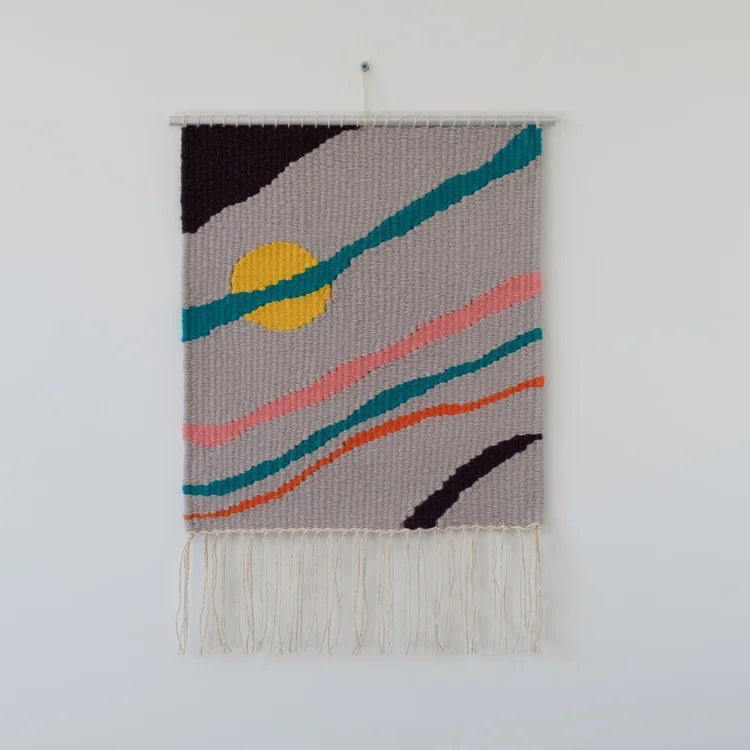 Arazzo contemporaneo in lana con base grigia, striature diagonali di colore arancione, rosa, verde e nero e cerchio giallo