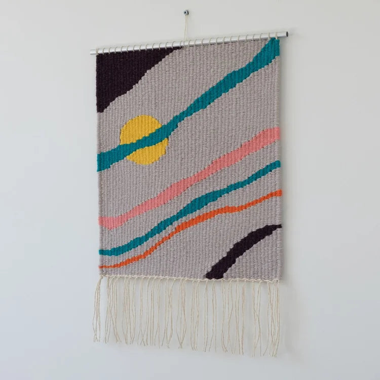 Arazzo contemporaneo in lana con base grigia, striature diagonali di colore arancione, rosa, verde e nero e cerchio giallo