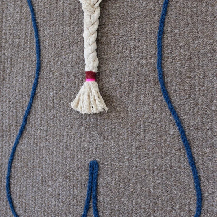 Arazzo contemporaneo in lana su base in cotone di Ilary Bottini con composizione astratta: profilo del corpo femminile tracciato in filo blu su tessuto grigio e treccia centrale in lana bianca.