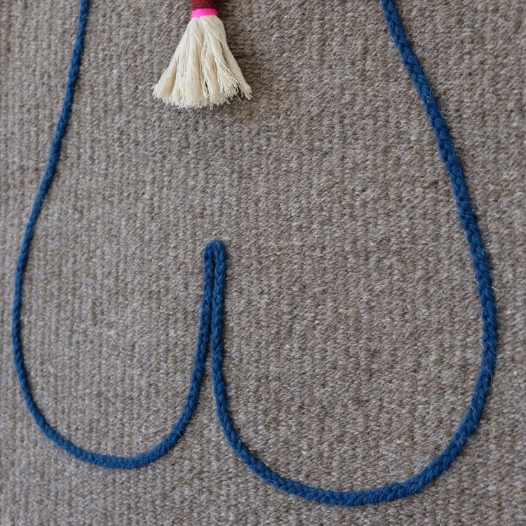 Arazzo contemporaneo in lana su base in cotone di Ilary Bottini con composizione astratta: profilo del corpo femminile tracciato in filo blu su tessuto grigio e treccia centrale in lana bianca.