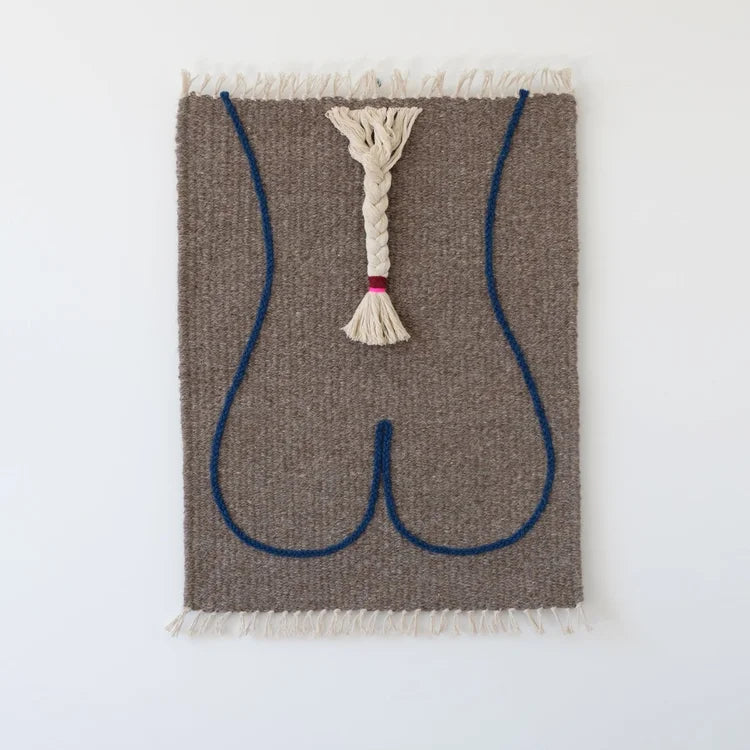 Arazzo contemporaneo in lana su base in cotone di Ilary Bottini con composizione astratta: profilo del corpo femminile tracciato in filo blu su tessuto grigio e treccia centrale in lana bianca.