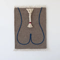Arazzo contemporaneo in lana su base in cotone di Ilary Bottini con composizione astratta: profilo del corpo femminile tracciato in filo blu su tessuto grigio e treccia centrale in lana bianca.