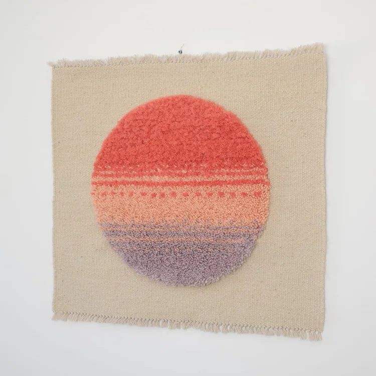 Arazzo contemporaneo Patagonian Sun di Ilary Bottini, opera tessile in lana tessuta a telaio verticale con base beige e cerchio annodato rosso, rosa e lilla